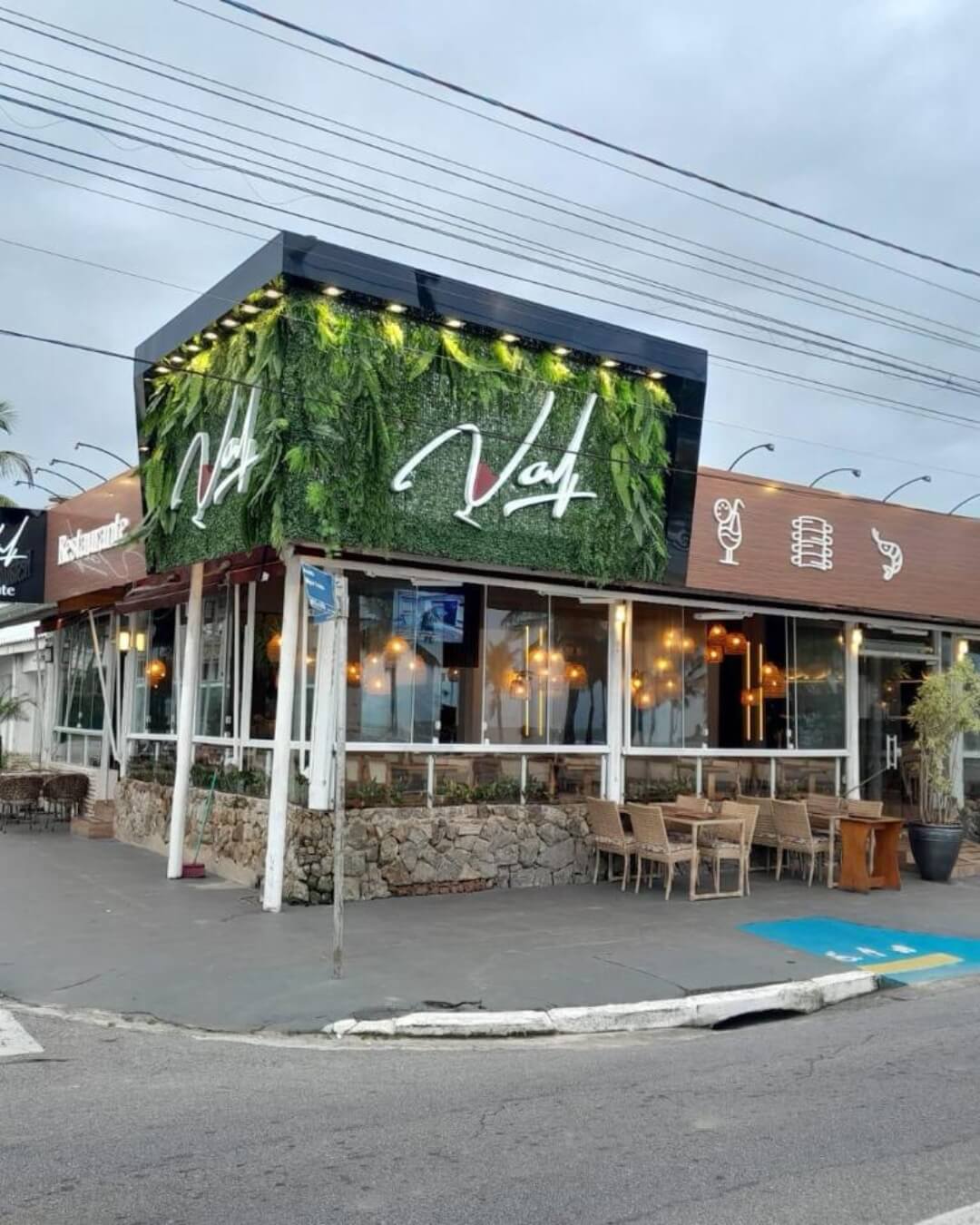Fachada de restaurante com jardim vertical e iluminação